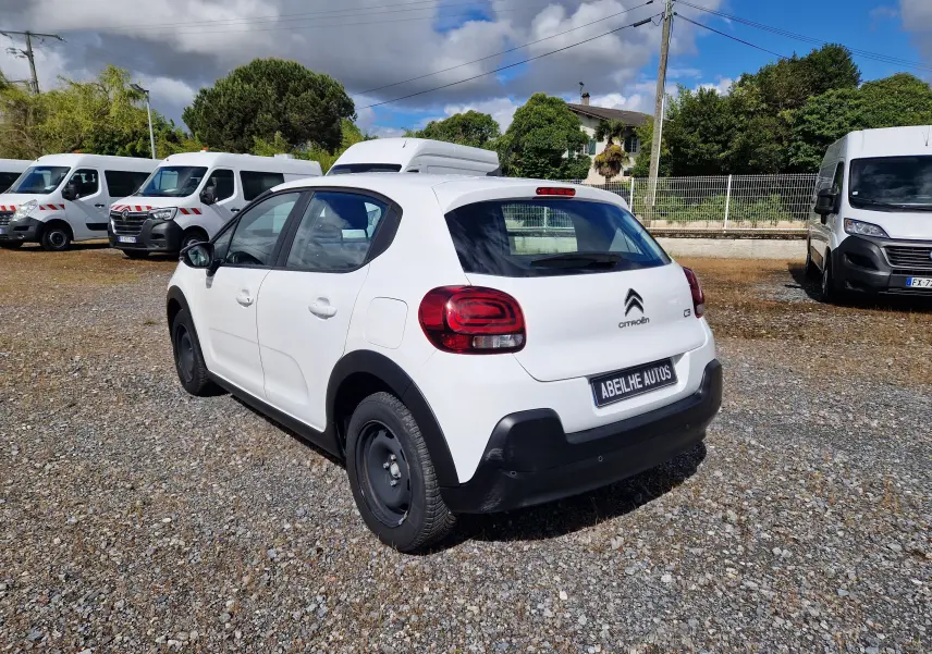 Vue 3/4 arrière droite d'une Citroën C3 Société blanche de 2021 avec jantes acier noires sur un parking extérieur.