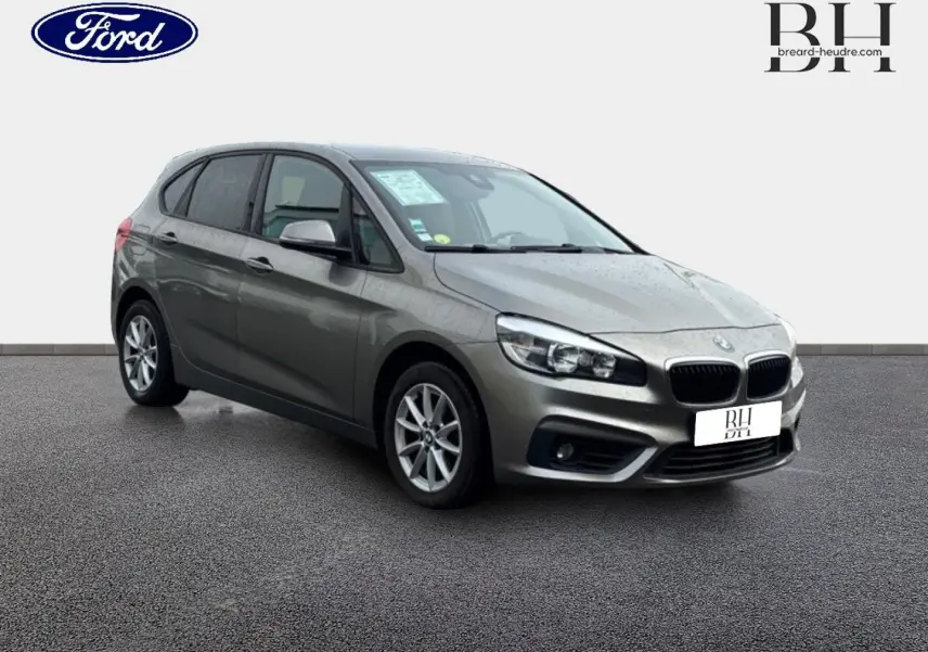 BMW Série 2 Active Tourer 216dA gris platine vue 3/4 avant droit sur sol gris, avec jantes alu et phares LED.