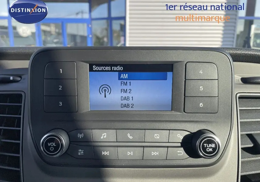 Vue rapprochée de la console centrale du Ford Transit Fourgon blanc 2023, affichant les options radio numériques.