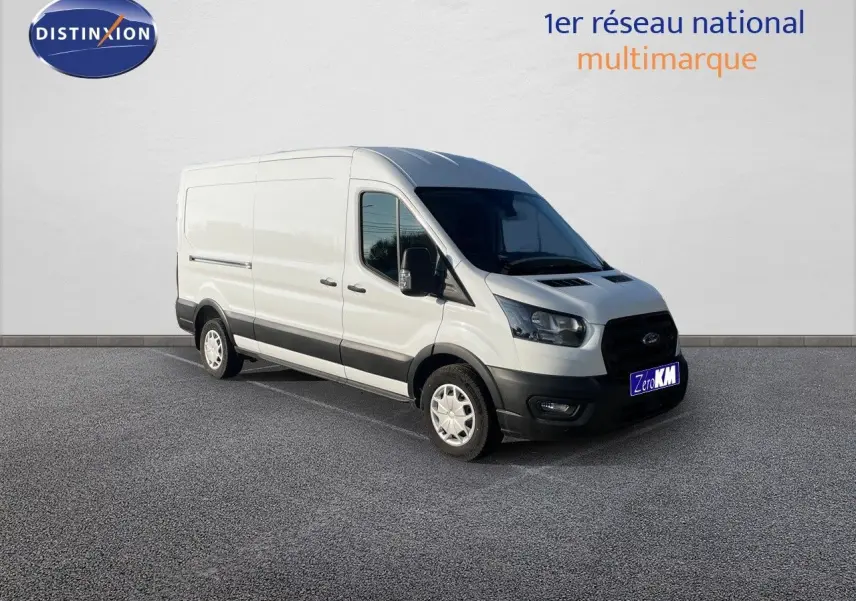 Fourgon Ford Transit blanc en 3/4 avant droit, avec pare-chocs noirs et jantes acier, stationné devant un mur blanc.