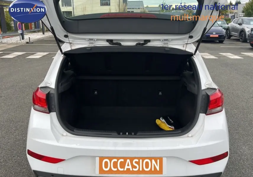 Vue arrière d'une Hyundai i30 blanche nacrée 2023 avec coffre ouvert montrant l'espace de chargement vide.