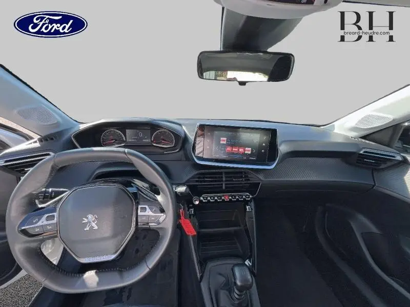 Vue intérieure avant du tableau de bord et volant noir d'une Peugeot 208 Affaire blanc banquise, avec écran tactile central allumé.