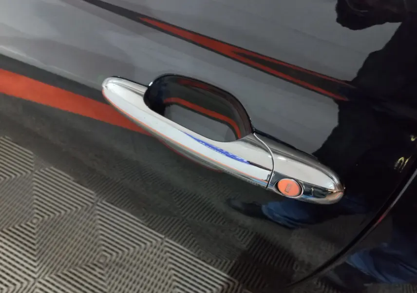 Poignée de porte chromée sur la portière noire d'une FIAT 500 1.2 8V 69ch Lounge, vue rapprochée côté droit.