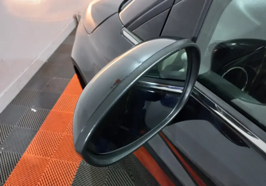 Rétroviseur côté gauche en gros plan sur une FIAT 500 noire, avec reflet de l'habitacle et carrosserie visible.