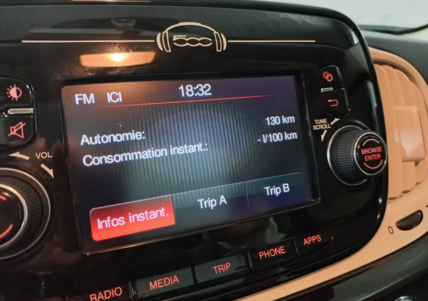 Écran tactile central noir de la Fiat 500 2018 affichant l'autonomie et les options multimédia, vue intérieure rapprochée.