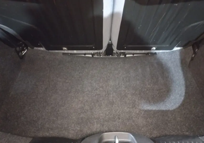 Vue du coffre arrière vide de la FIAT 500 noire, montrant la moquette grise et le dos des sièges rabattables.