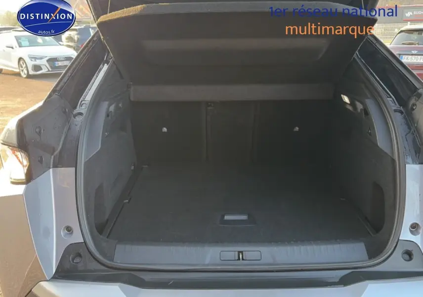 Coffre ouvert d’un Peugeot 3008 gris vu de l’arrière, montrant un espace de chargement spacieux et propre.