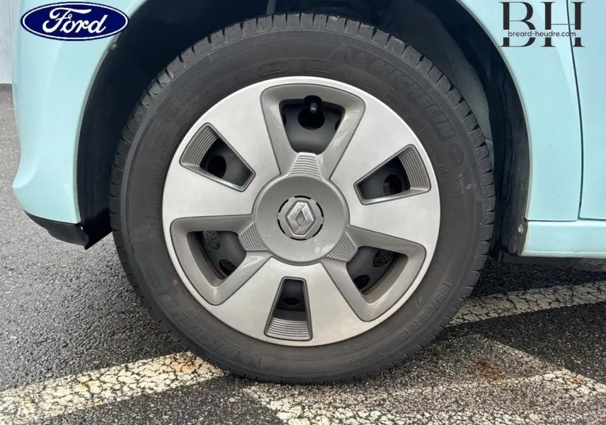 Gros plan sur la roue avant gauche d'une Renault Twingo bleu dragée avec jante en alliage gris.