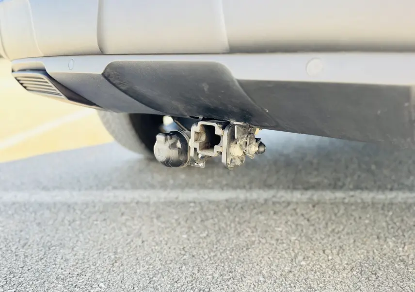 Gros plan sur l'attelage démontable sans outils sous le pare-chocs arrière du Peugeot 3008 gris Artens.