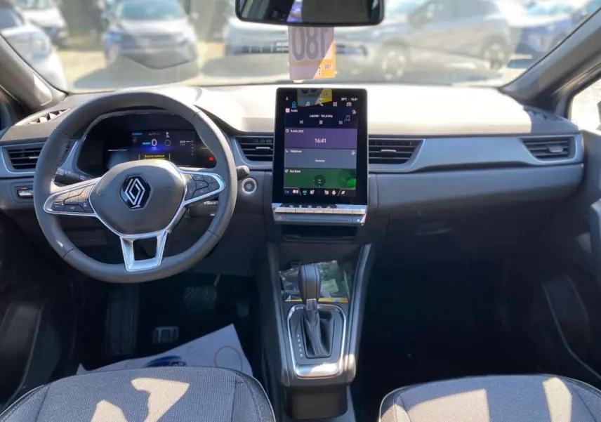 Vue intérieure avant du Renault Captur 2025, tableau de bord moderne avec écran tactile vertical et volant multifonction.