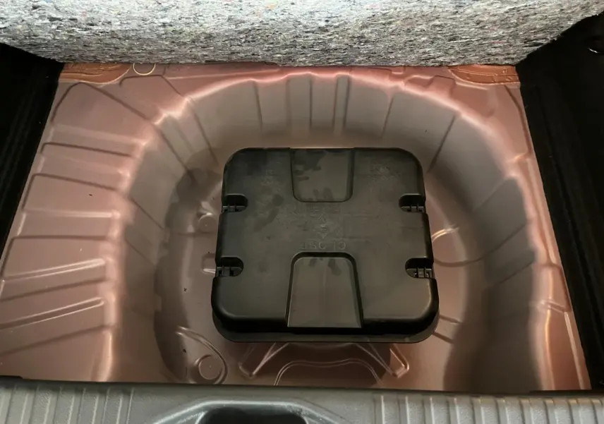 Coffre ouvert montrant le rangement sous plancher rouge métallisé avec boîte à outils noire Renault.