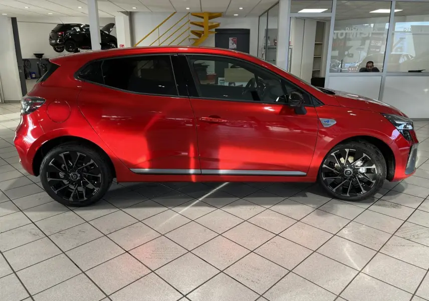 Profil droit d'une Renault Clio 1.0 Tce 90 Esprit Alpine rouge avec jantes noires et badge Alpine sur aile avant.