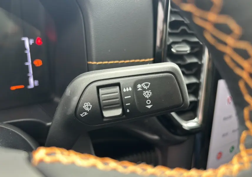 Gros plan sur la commande des essuie-glaces du Ford Ranger 3.0 V6 240 Wildtrak Plus 2025 avec surpiqûres orange visibles.