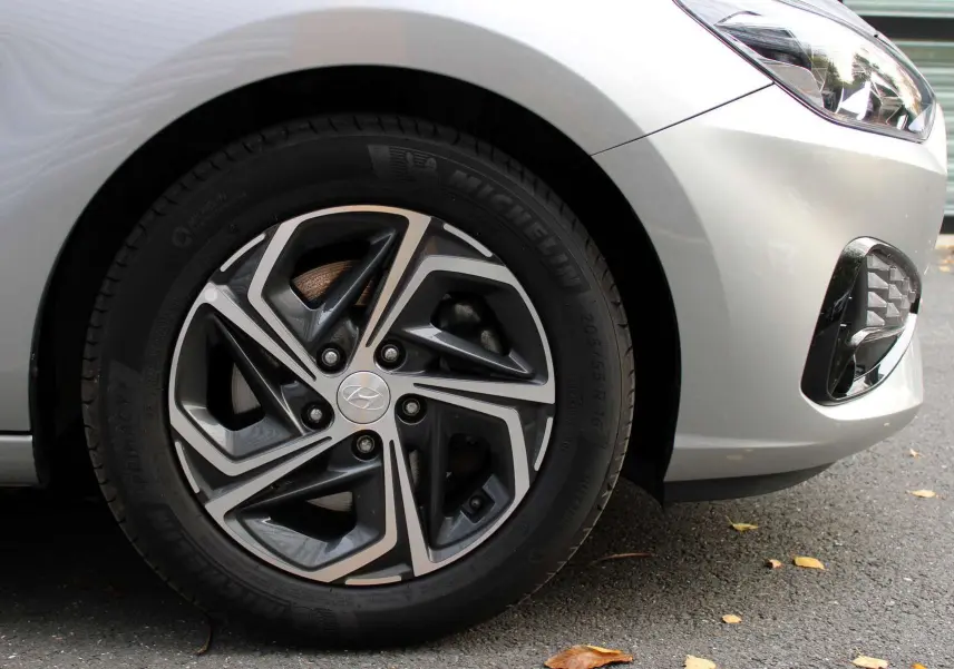 Gros plan sur la roue avant gauche argentée d'une Hyundai i30 SW 2024 avec jante alliage et carrosserie grise.