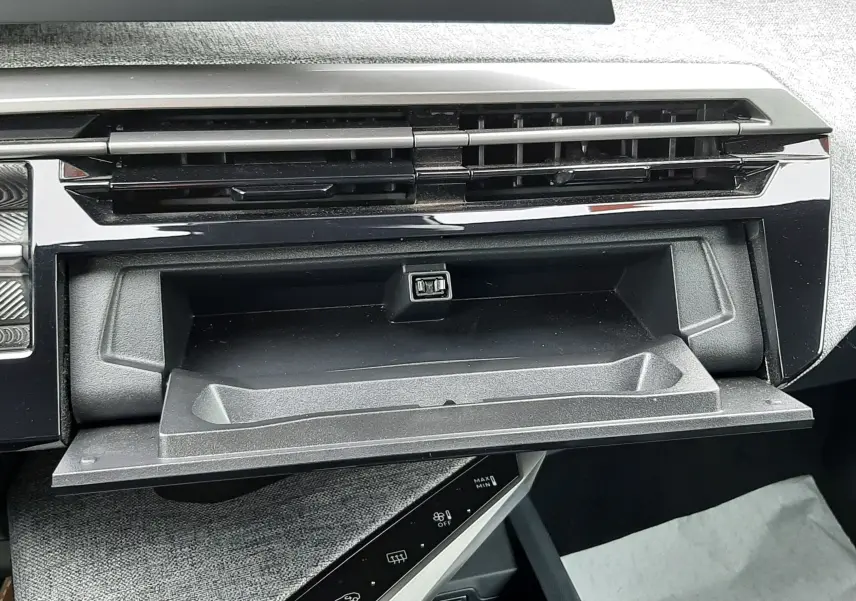 Intérieur du Peugeot 3008 III Hybrid 145 Allure, vue rapprochée de la boîte à gants ouverte et de la console centrale noire.