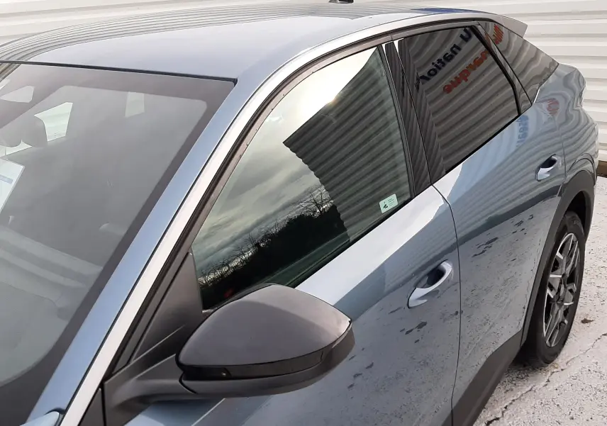 Vue 3/4 arrière côté gauche du Peugeot 3008 III HYBRID 145 Allure bleu Ingaro avec rétroviseur noir et vitres teintées.