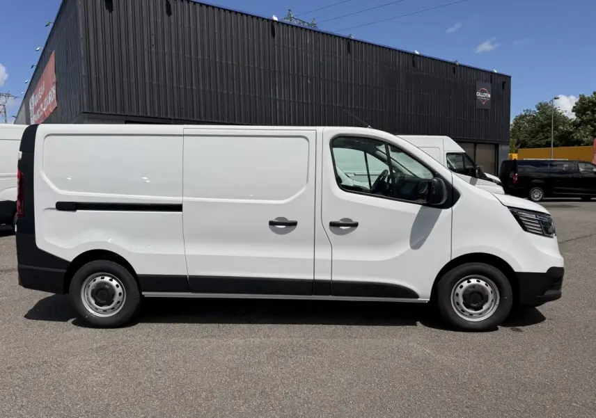 Renault Trafic Fourgon blanc vu de profil côté gauche, avec porte latérale coulissante et jantes acier.