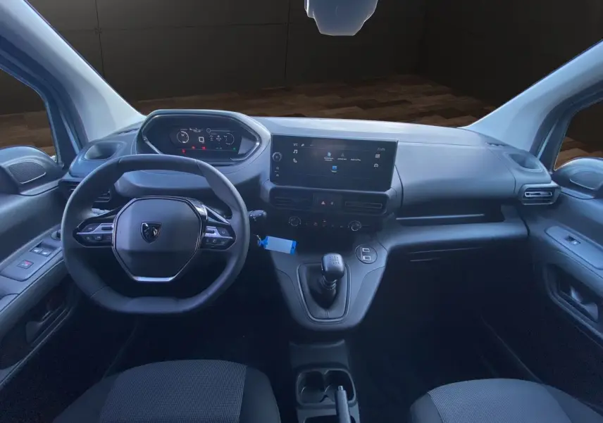 Intérieur du Peugeot Partner 2024 montrant le tableau de bord moderne avec écran tactile et volant multifonction noir.