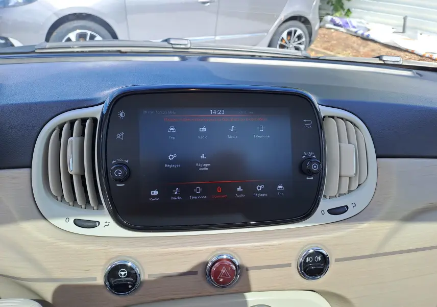 Tableau de bord clair de la Fiat 500 blanche 2022, avec écran tactile central et aérateurs ovales beige.