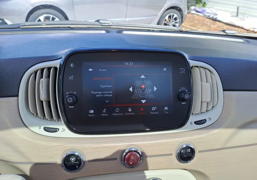 Tableau de bord clair et écran tactile central de la Fiat 500 blanche, vue intérieure frontale détaillée.