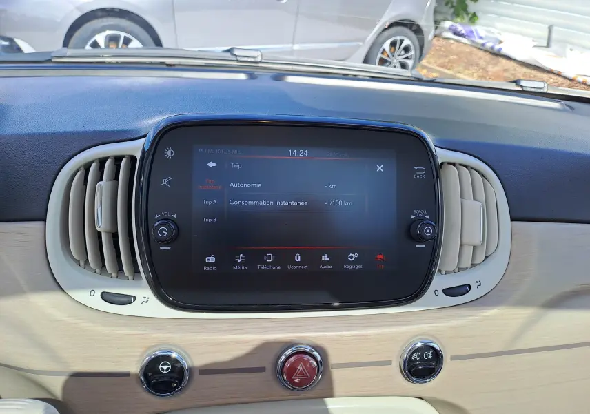 Écran tactile central et aérateurs beige sur tableau de bord bois clair d'une Fiat 500 blanche 2022 hybride.