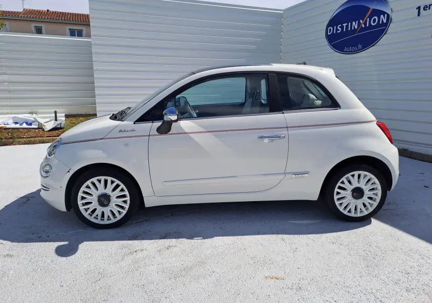 Profil côté droit d'une FIAT 500 blanche 2022 avec ligne rouge fine et jantes blanches ajourées, stationnée en extérieur.