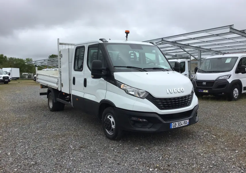IVECO Daily Chassis double cabine blanc vu en 3/4 avant droit, avec benne, coffre latéral et roues jumelées.