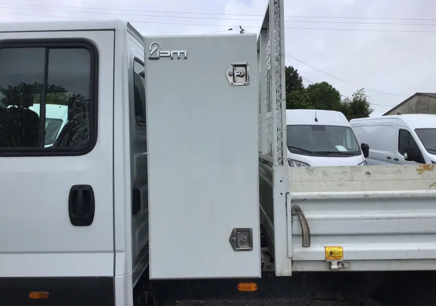 Vue latérale droite du camion blanc Iveco Daily Chassis double cabine avec benne et coffre latéral fermé.