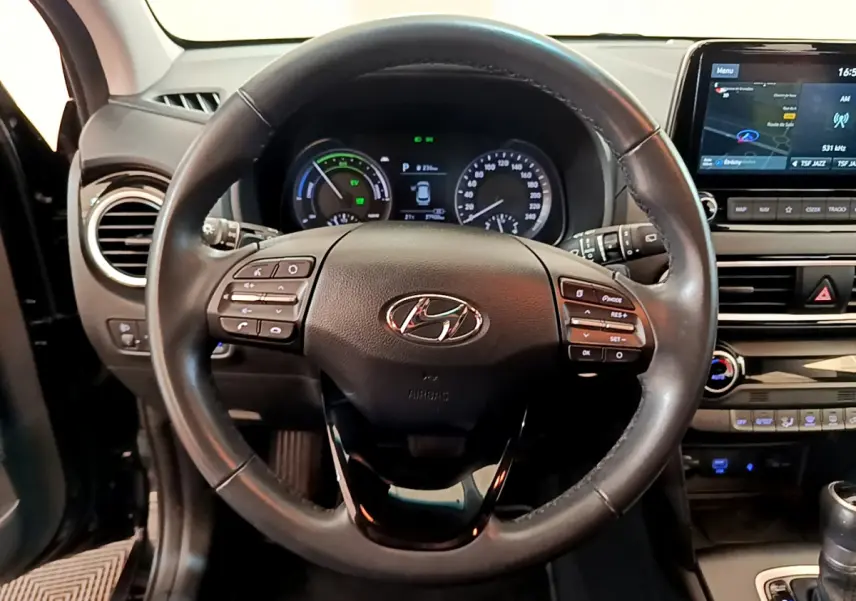 Vue centrée sur le volant cuir noir d'une Hyundai Kona 2020, avec tableau de bord et écran tactile de navigation visibles.