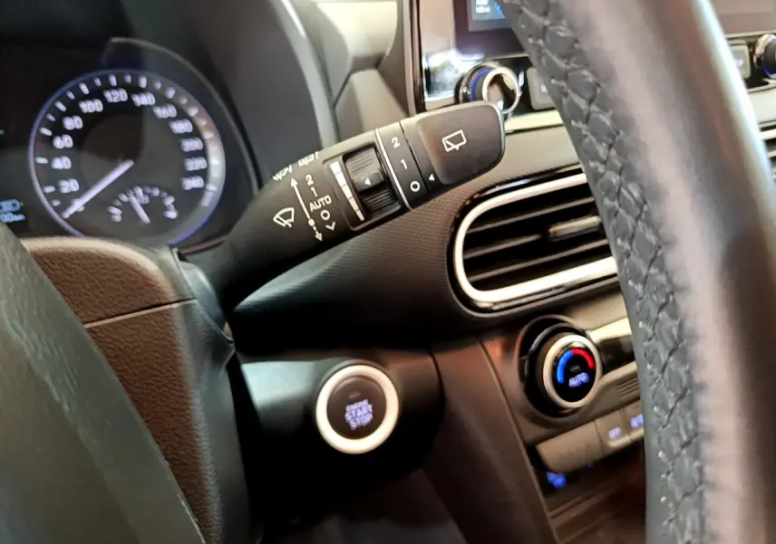 Gros plan intérieur sur le volant noir et la commande essuie-glace du Hyundai Kona hybride 2020 avec bouton démarrage.