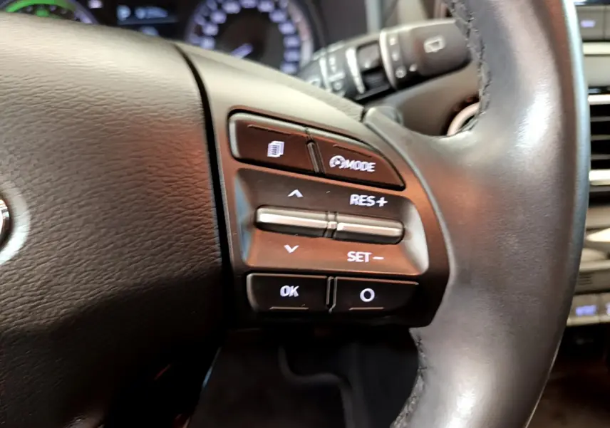 Gros plan sur les commandes du volant cuir du Hyundai Kona 1.6 GDi Hybrid 2020, boutons de régulateur de vitesse visibles.
