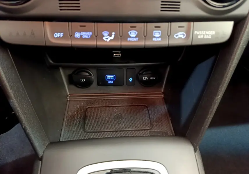 Détail de la console centrale du Hyundai Kona noir 2020 montrant ports USB, prise 12V et zone de recharge sans fil Qi.