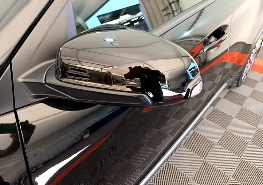 Gros plan sur le rétroviseur côté gauche noir brillant du Hyundai Kona 1.6 GDi Hybrid 2020, avec reflet de l'environnement intérieur.