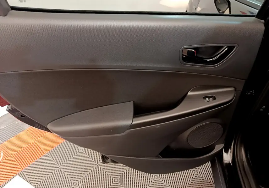 Gros plan sur la portière intérieure côté gauche noire du Hyundai Kona 2020 avec commande de vitre et haut-parleur intégré.