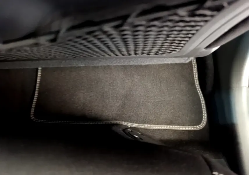 Tapis de sol noir avec surpiqûres blanches sous le filet de rangement, intérieur d’un Hyundai Kona hybride 2020.