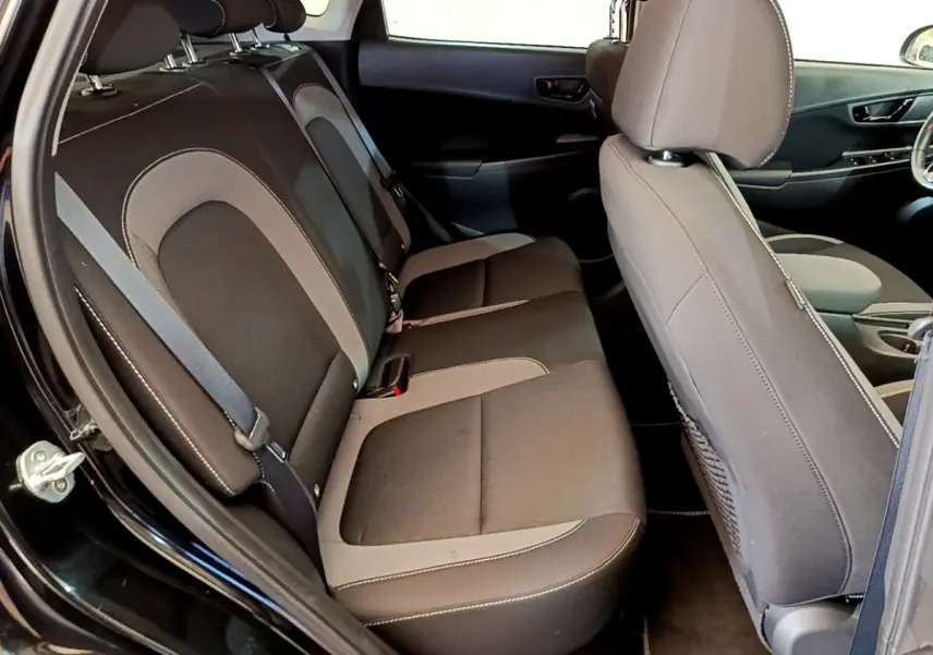 Vue intérieure côté gauche montrant la banquette arrière et le siège avant du Hyundai Kona noir 2020 hybride.