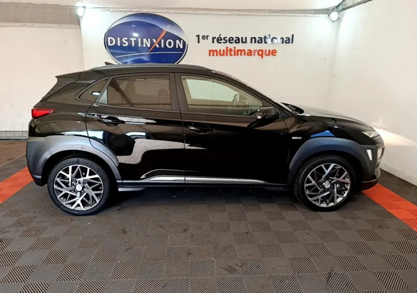 Profil côté gauche d'un Hyundai Kona noir 2020 hybride, avec jantes alliage et protections d'ailes grises.
