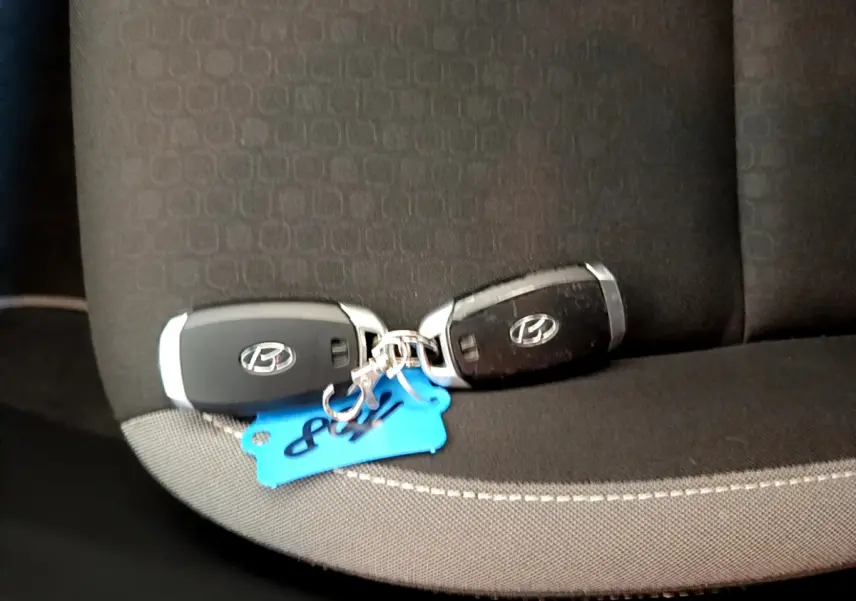 Deux clés Hyundai noires posées sur un siège tissu gris foncé à coutures apparentes, intérieur du Kona 2020.