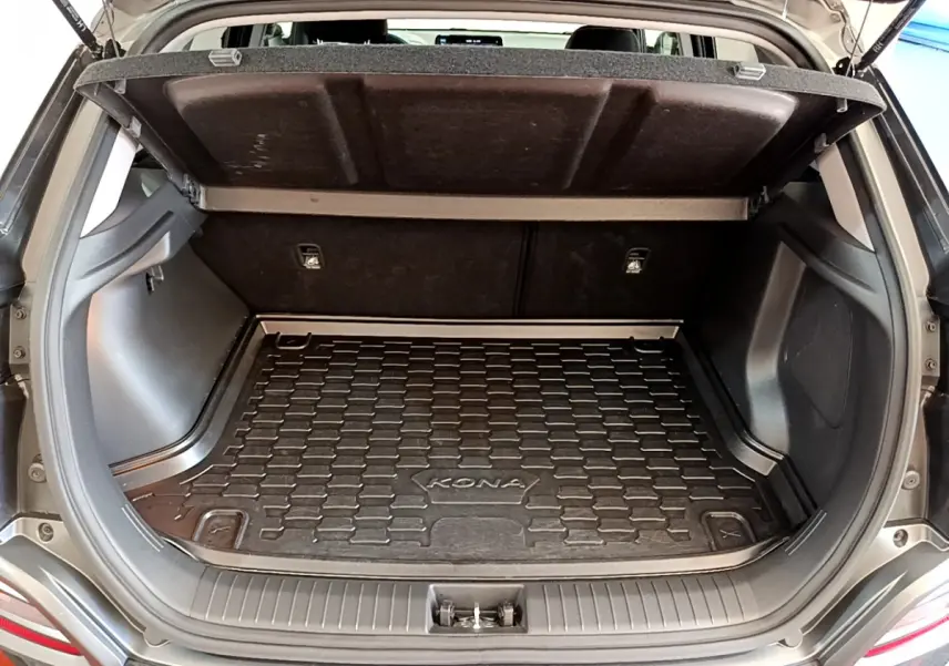 Coffre ouvert d'un Hyundai Kona noir 2020, montrant le tapis de coffre spécifique avec logo KONA.