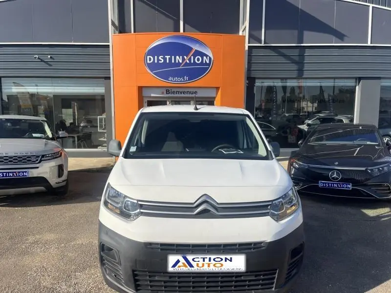 Vue frontale d'un Citroën Berlingo blanc Banquise avec calandre distinctive, garé devant un concessionnaire.
