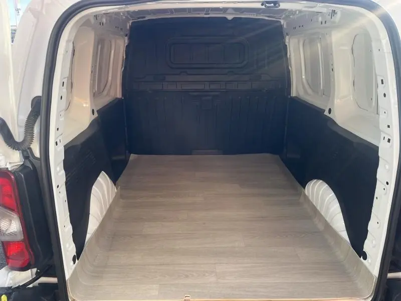 Vue intérieure arrière du Citroën Berlingo Fourgon blanc Banquise, montrant la zone de chargement vide avec plancher en bois clair.