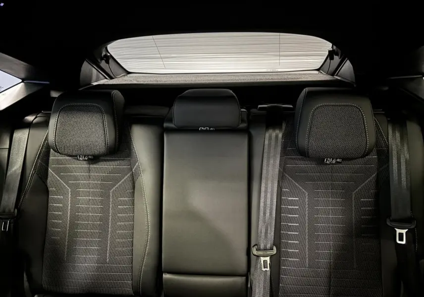 Vue arrière intérieure des sièges arrière noirs du Peugeot 3008 Hybrid 2025 avec appuie-têtes et ceintures visibles.