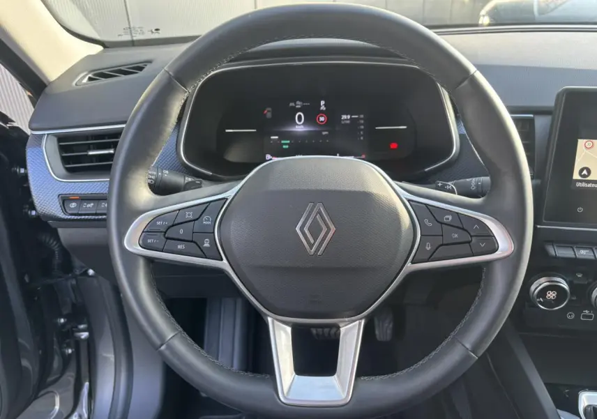 Vue frontale du volant noir de la Renault Arkana 2025 avec tableau de bord numérique et commandes intégrées.