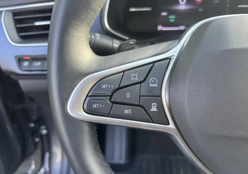 Gros plan sur les commandes à gauche du volant noir du Renault Arkana 2025 avec tableau de bord numérique en arrière-plan.