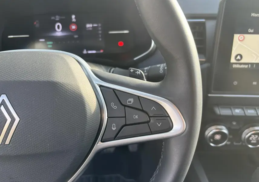 Gros plan sur le volant noir et les commandes multifonctions côté droit du Renault Arkana 2025, avec écran tactile en arrière-plan.