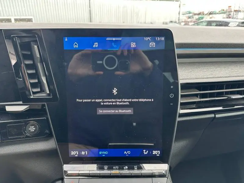 Écran tactile central du tableau de bord du Renault Austral 2025, affichant la connexion Bluetooth, entouré de commandes et aérateurs.