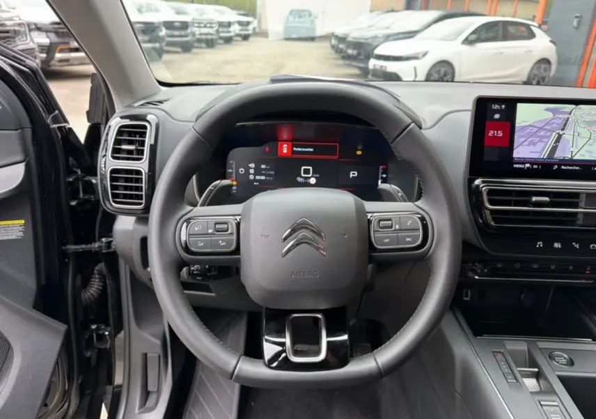 Vue intérieure centrée sur le volant cuir multifonctions noir du Citroën C5 Aircross 2025 avec écran tactile GPS allumé.