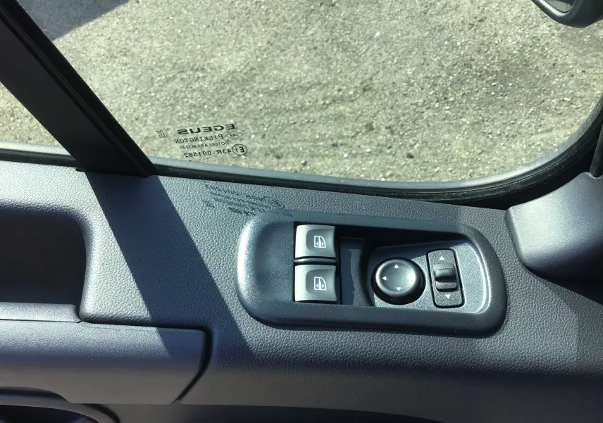 Commande des vitres électriques et réglage des rétroviseurs sur la porte côté gauche d'un Renault Master gris étoile 2024.