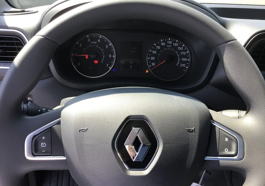 Vue rapprochée du volant gris avec logo Renault et tableau de bord du Master L2H2 2024 en arrière-plan.