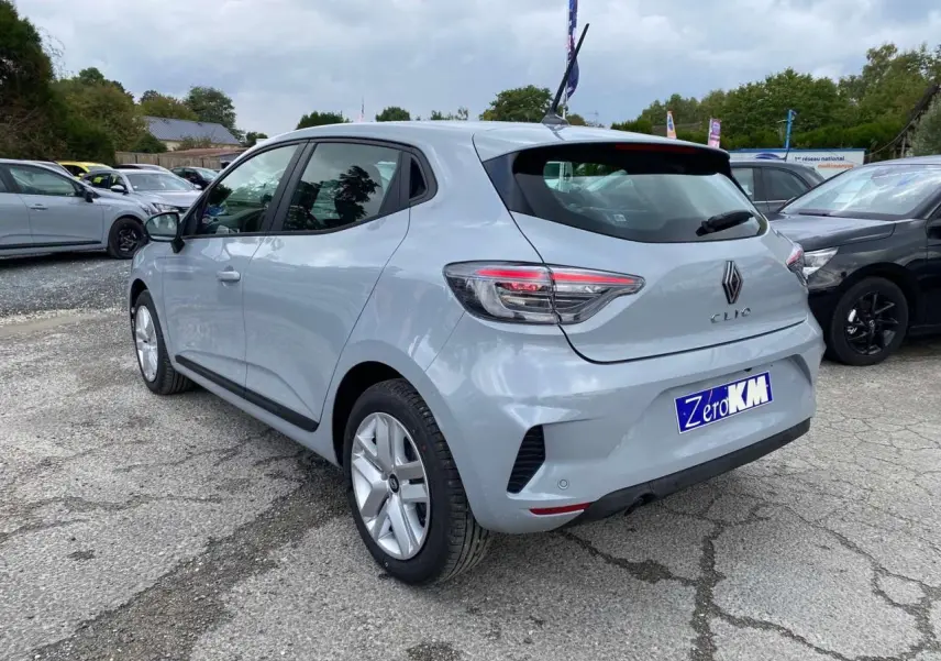 Renault Clio 2025 gris Rafale vue 3/4 arrière droit, avec feux LED et jantes alliage visibles sur parking.